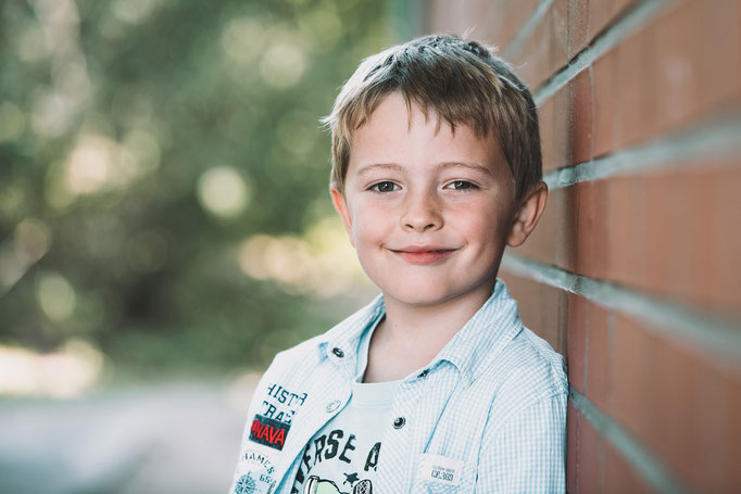 Lächelnder Junge an eine Mauer gelehnt auf einem Schulfoto