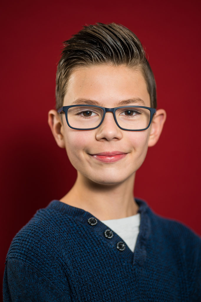 Junge vor rotem Hintergrund auf einem Schulfoto