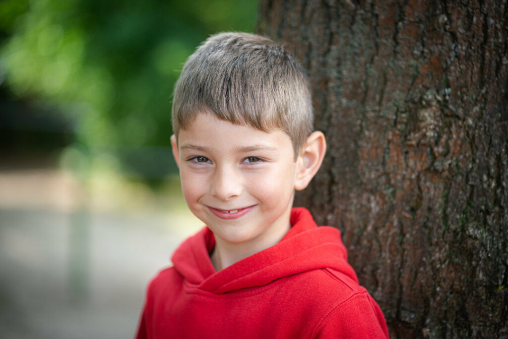Lächelnder Junge an einem Baum gelehnt auf einem Schulfoto